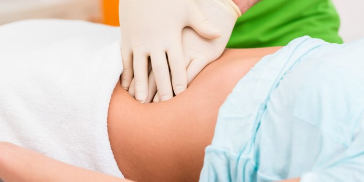 Ein Therapeut massiert den Bauch einer Frau.
